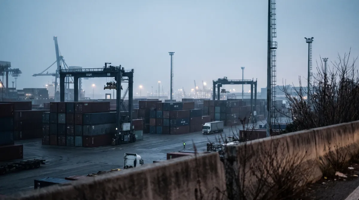 Vista dall'alto di un piazzale container all'alba con gru a portale in controluce