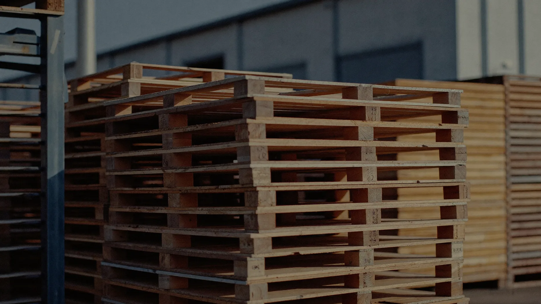 Cataste di pallet in legno grezzo in un piazzale industriale